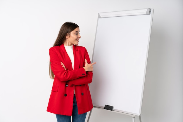 Jovem mulher dando uma apresentação no quadro branco, dando uma apresentação no quadro branco e apontando-o