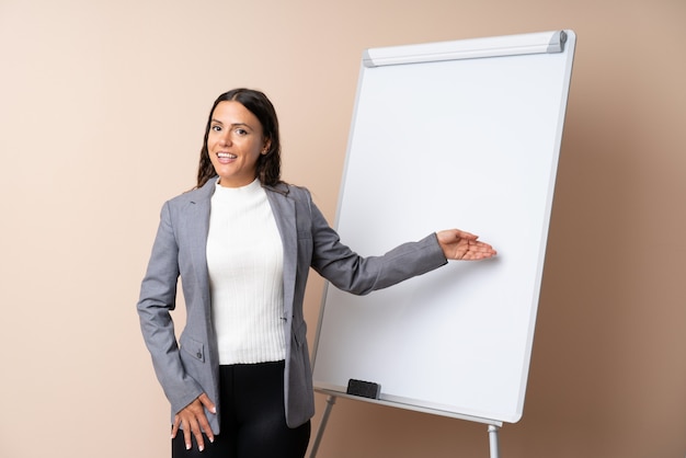 Jovem mulher dando uma apresentação no quadro branco, dando uma apresentação no quadro branco e apontando-o