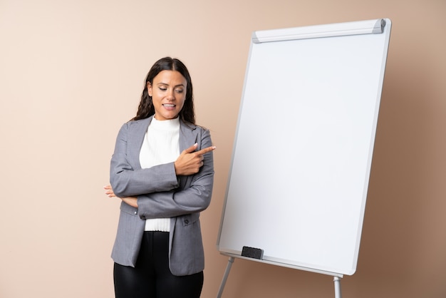 Jovem mulher dando uma apresentação no quadro branco, dando uma apresentação no quadro branco e apontando-o