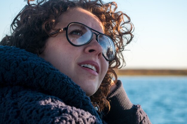 Jovem mulher de cabelos cacheados de óculos em passeio de barco.