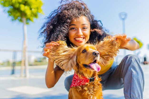 Jovem mulher de cabelos cacheados felizes brincando com cocker americano no beco da praia em fundo de palmas de luz solar