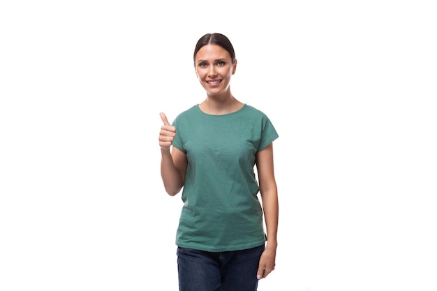 Jovem mulher de cabelos pretos com uma camiseta básica verde sorri afavelmente em um fundo branco com espaço de cópia