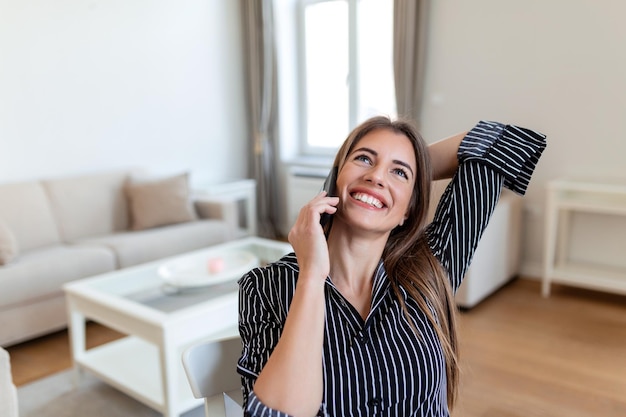 Foto jovem mulher de escritório falando com alguém em seu celular enquanto olha para longe com expressão facial feliz