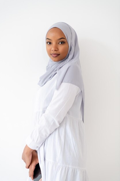 jovem mulher de negócios africana muçulmana moderna usando smartphone vestindo roupas hijab isoladas no fundo branco