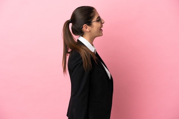 Jovem mulher de negócios caucasiana isolada em um fundo rosa rindo na posição lateral