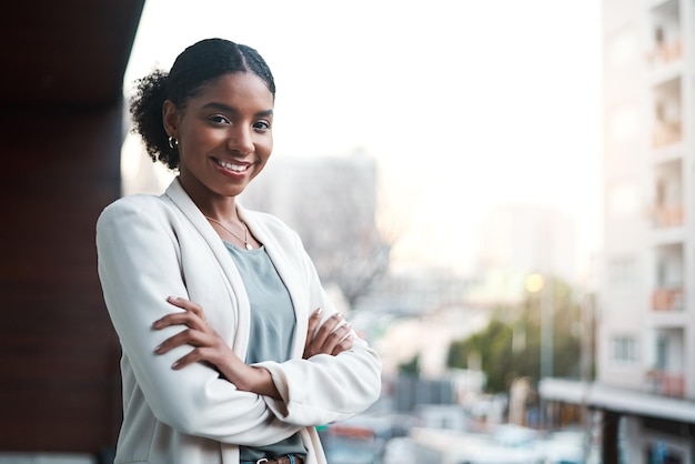 Jovem mulher de negócios confiante e ambiciosa de braços cruzados em uma varanda do lado de fora da cidade Retrato de um profissional corporativo feminino feliz sorridente e positivo pronto para um novo começo