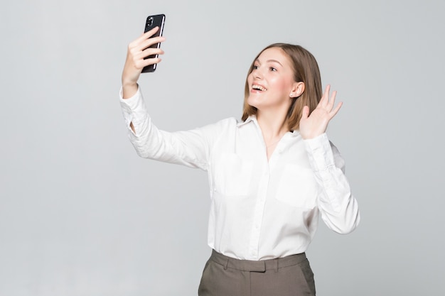 Jovem mulher de negócios cumprimentando alguém em videochamada no telefone