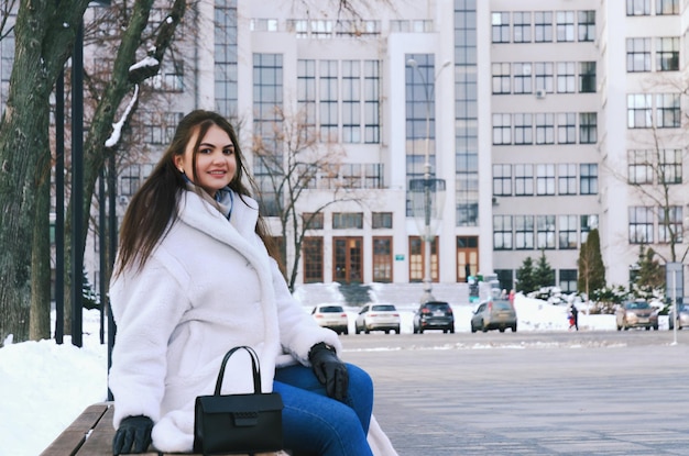 jovem mulher de negócios elegante em roupas casuais de inverno, jaqueta branca. Andando. rua da cidade, conversando