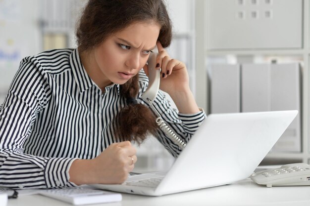 Jovem mulher de negócios trabalhando no escritório, usando um laptop