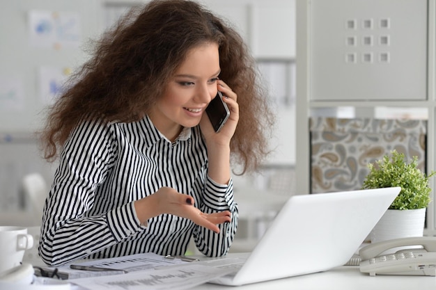 Foto jovem mulher de negócios trabalhando no escritório, usando um laptop