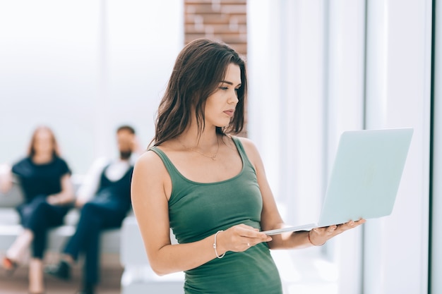 Jovem mulher de negócios usa laptop enquanto está no escritório. Foto com espaço de cópia