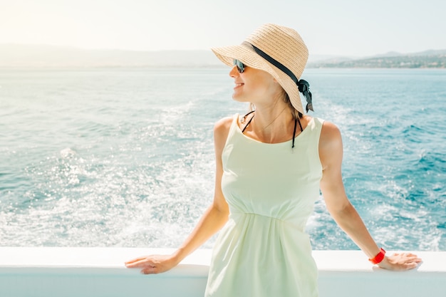 Jovem mulher de pé em um barco durante as férias de verão a sorrir