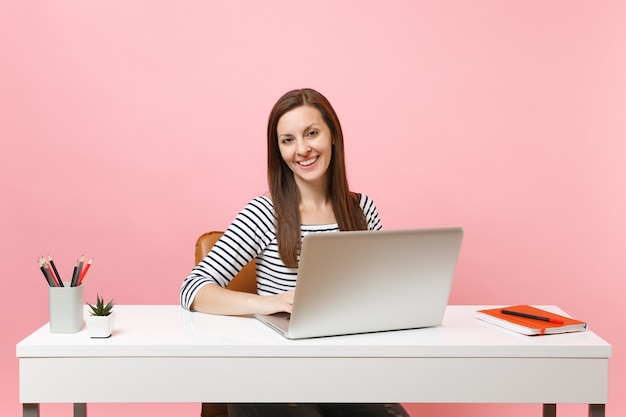 Jovem mulher de sucesso com roupas casuais, trabalhando em um projeto com laptop enquanto está sentado no escritório