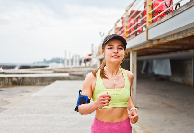 Jovem mulher decidida corre ao ar livre e ouve música. Corrida matinal