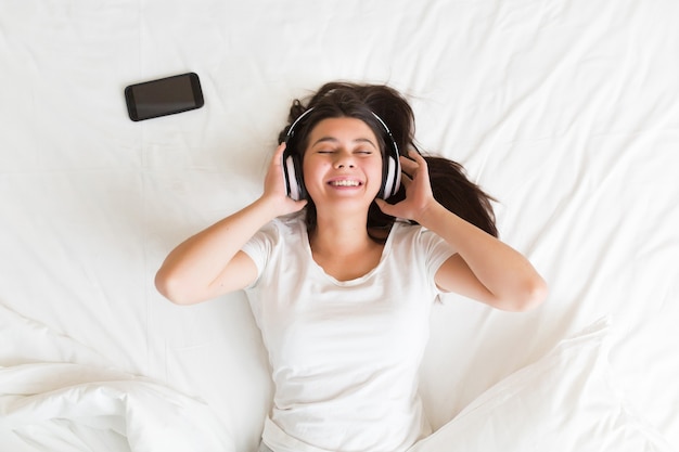 Jovem mulher deitada no sofá ouvindo música relaxante com os olhos fechados