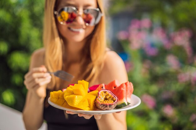 Foto jovem mulher descansando em uma varanda com um prato de frutas, trabalho, equilíbrio, relaxamento, qualidade saudável