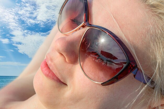 Jovem mulher descansando na praia em óculos de sol. conceito de turismo e recreação