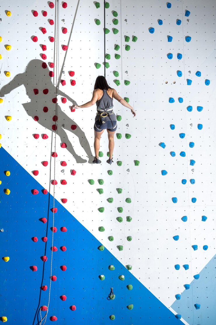 Foto jovem mulher descendo de uma parede de uma parede de escalada