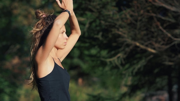 Jovem mulher desfrutando de solidão e liberdade na colina verde ao nascer do sol Garota de ioga tendo meditação nas montanhas da manhã de verão Bela modelo feminina fazendo exercícios na floresta de montanha