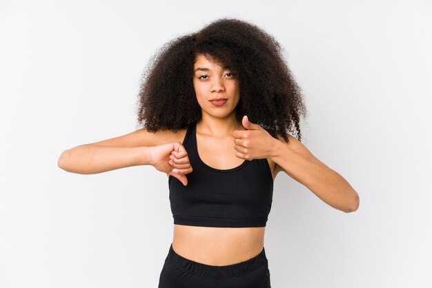 Jovem mulher desportiva afro-americana mostrando os polegares para cima e os polegares para baixo, difícil escolher o conceito