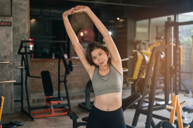 Jovem mulher desportiva alongando-se na academia, conceito de esporte fitness