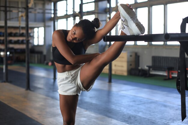 Jovem mulher desportiva alongando-se no ginásio.