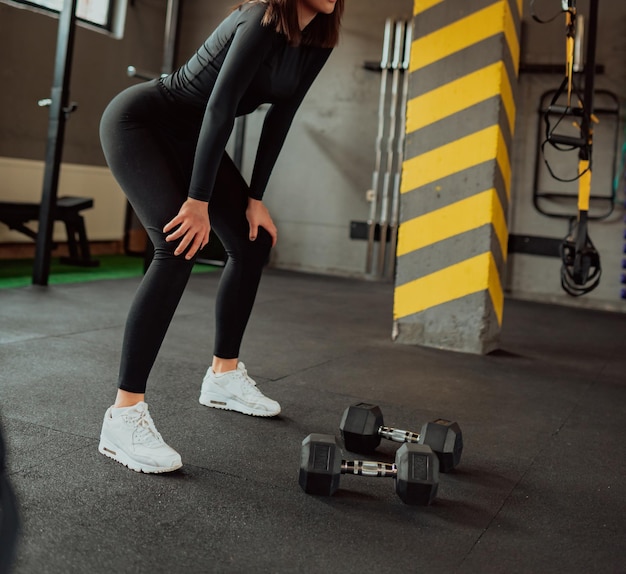 Jovem mulher desportiva em sportswear cansado e fazer uma pausa no ginásio.