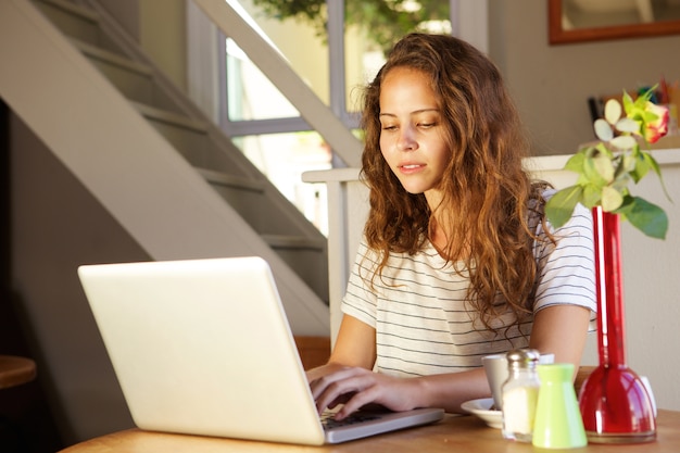 Jovem mulher digitando no laptop em casa