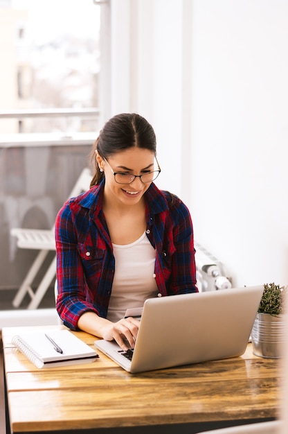 Jovem mulher digitando no teclado do laptop em casa