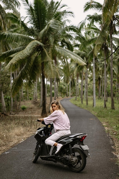 Jovem mulher dirigindo uma vida tropical de ciclomotor