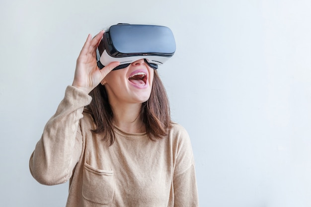 Jovem mulher do sorriso que veste usando auriculares do capacete dos vidros da realidade virtual vr no fundo branco. óculos de smartphone usando com realidade virtual. tecnologia, simulação, alta tecnologia, conceito de videogame.