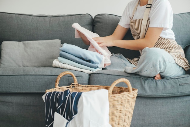 Foto jovem mulher dobrando roupas no sofá em casa