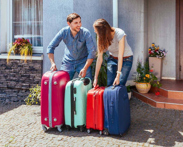 Jovem mulher e homem com muita mala perto de casa pronta para viajar