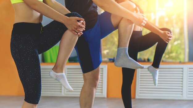 Jovem mulher e homem, estendendo-se no estúdio de fitness