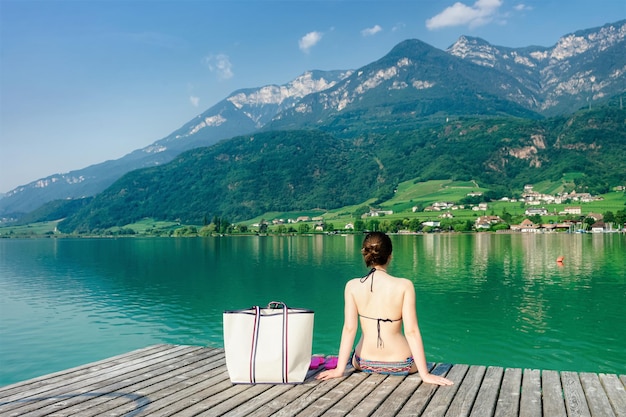 Jovem mulher e paisagem verde com lago Caldaro e montanhas dos Alpes em fundo de belo estilo. Garota nas férias de verão ou paisagem de manhã de primavera, Tirol da Itália. Tirol do Sul italiano. Mídia mista.