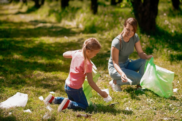 Jovem mulher e seu filho coletando gargabe no parque