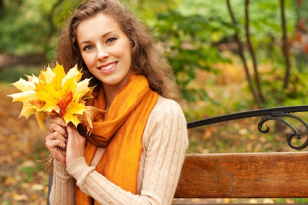 Jovem mulher elegante com folhas de outono