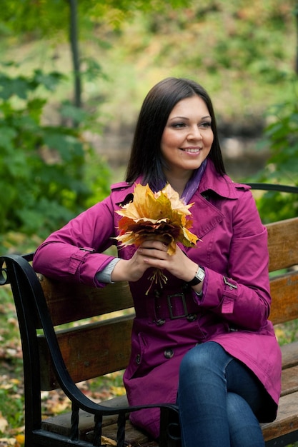 Jovem mulher elegante com folhas de outono