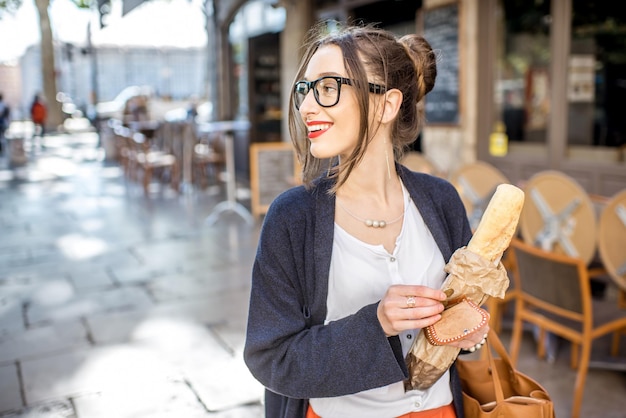 Jovem mulher elegante comprando uma baguete francesa em pé na rua na cidade de Lyon