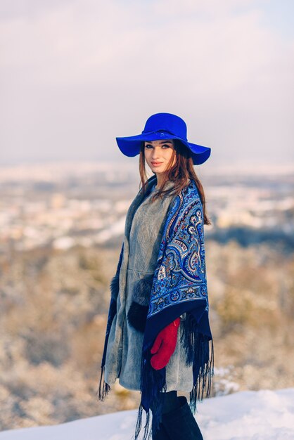 Jovem mulher elegante de chapéu azul e lenço andando no parque de inverno