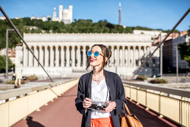 Jovem mulher elegante em pé com uma câmera fotográfica na passarela na cidade velha de Lyon, França