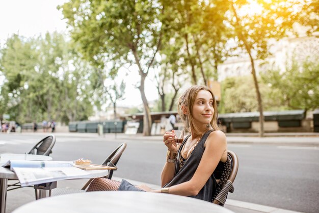 Jovem mulher elegante tomando café ao ar livre em um café em Paris