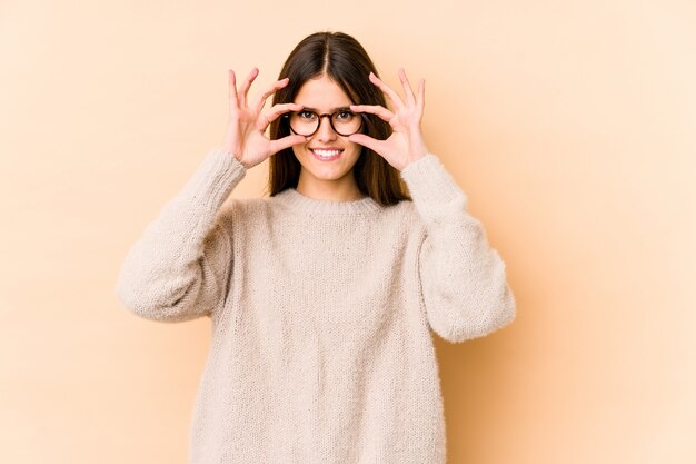 Jovem mulher em bege mostrando sinal bem sobre os olhos