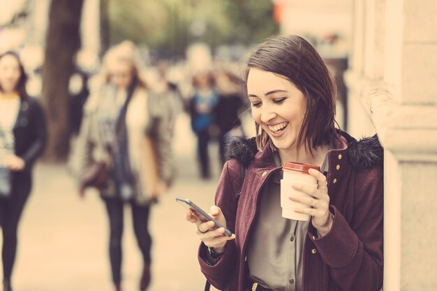 Jovem mulher em Londres com chá e telefone inteligente