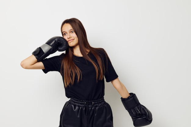 Foto jovem mulher em luvas de boxe de uniforme esportivo preto posando estilo de vida inalterado