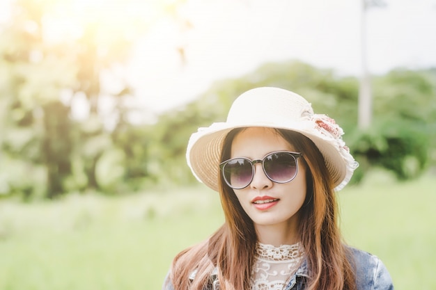 Foto jovem mulher em um campo, óculos de sol arredondados que têm o divertimento ao ar livre no campo.