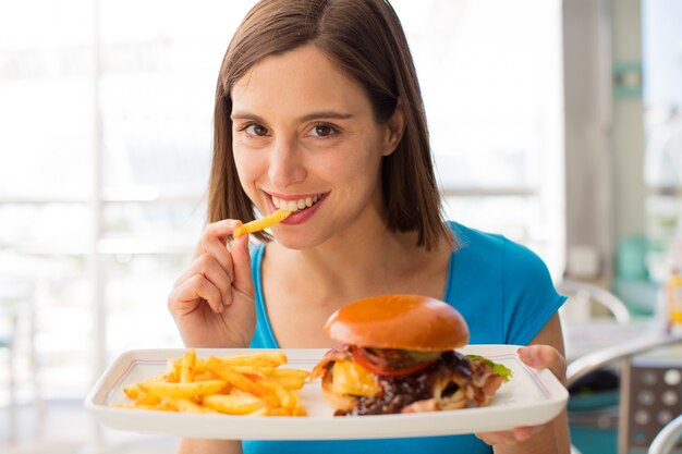 Foto jovem mulher em um restaurante com um hambúrguer