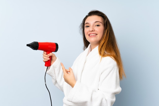 Jovem mulher em um roupão de banho com secador de cabelo e apontando-o