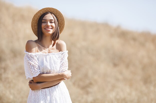 Jovem mulher em um vestido branco e chapéu