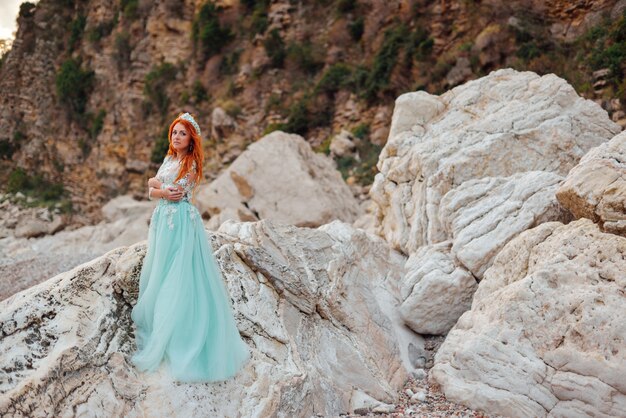 Jovem mulher em um vestido de luxo fica na costa do mar Adriático